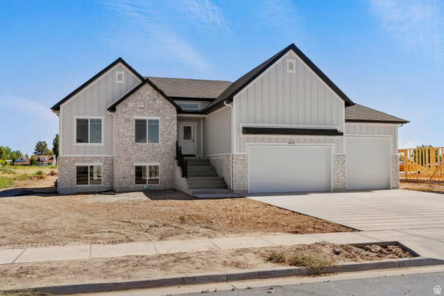 5777 West 4100 South Hooper, UT 84315 - Photo 1 of 41 View of front of home with stone siding, board and batten siding, an attached garage, concrete driveway, and roof with shingles