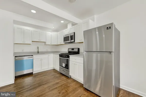 a kitchen with granite countertop a refrigerator stove top oven and sink