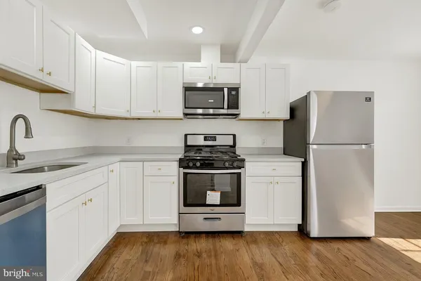a kitchen with stainless steel appliances a sink cabinets and a wooden floor