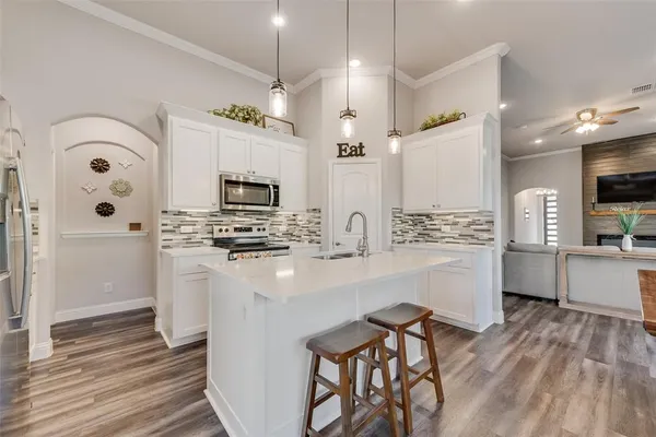 a kitchen with stainless steel appliances a stove top oven a sink dishwasher and a refrigerator with wooden floor