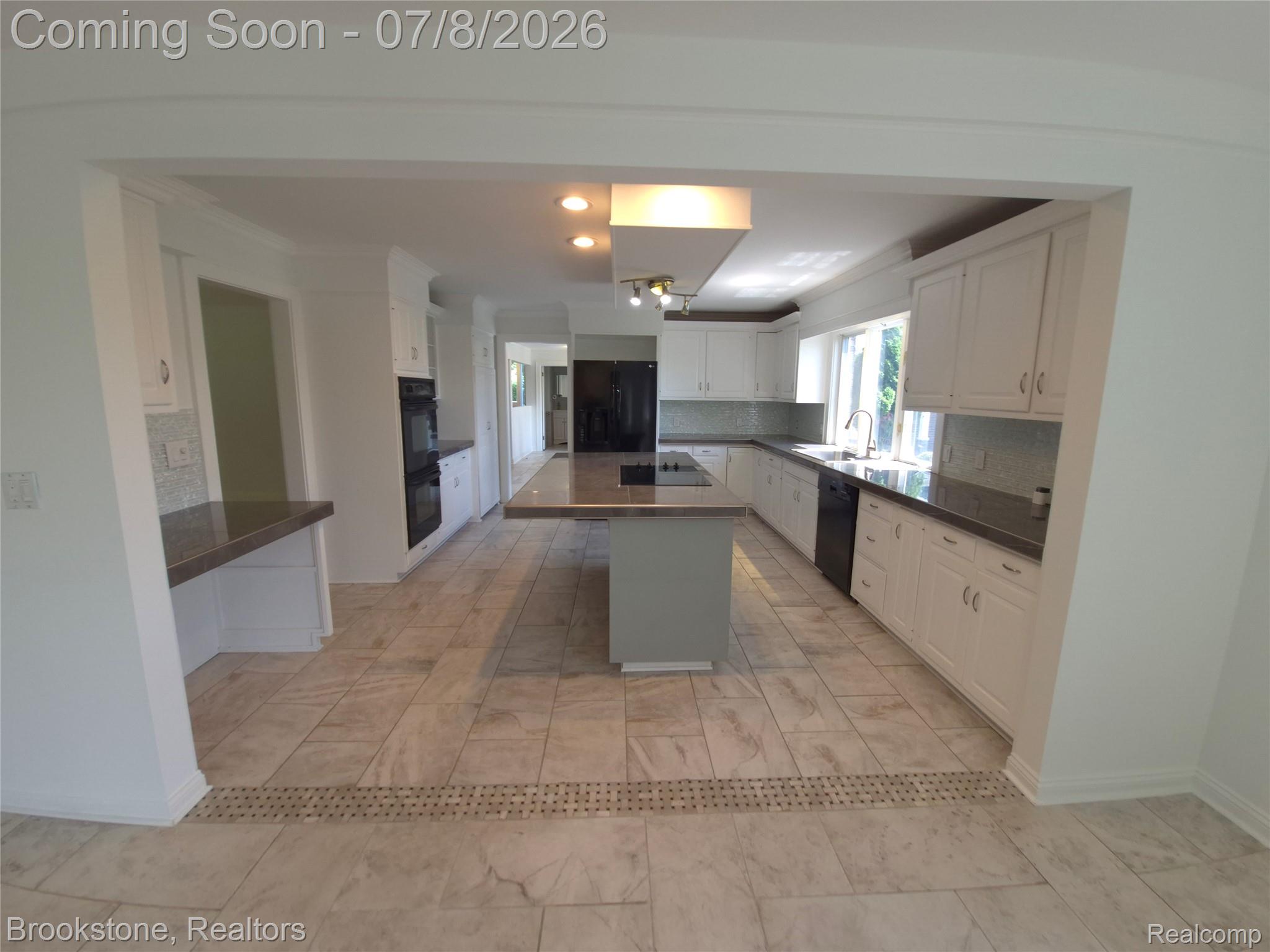 4140 South Henderson Road Davison, MI 48423 - Photo 25 of 98 Spacious kitchen featuring an expansive center island with cooktop, white cabinetry, dark countertops, built-in double ovens, and large-format tile flooring