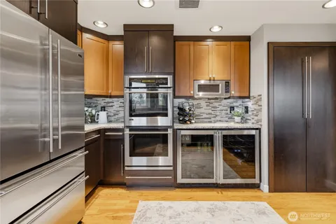 a dining hall with stainless steel appliances kitchen island granite countertop a dining table chairs and a refrigerator
