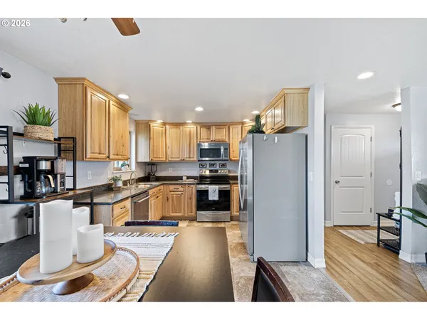 a kitchen with stainless steel appliances kitchen island granite countertop a refrigerator a stove a sink dishwasher and white cabinets with wooden floor