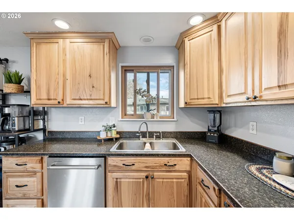 a kitchen with stainless steel appliances granite countertop white cabinets a window and a sink