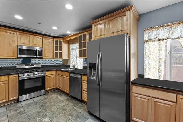 a kitchen with stainless steel appliances granite countertop a refrigerator a stove a sink and a microwave