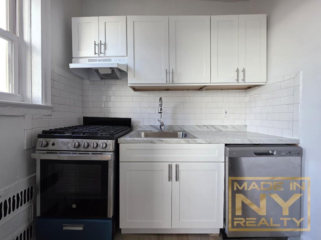 a kitchen with granite countertop white cabinets and a stove