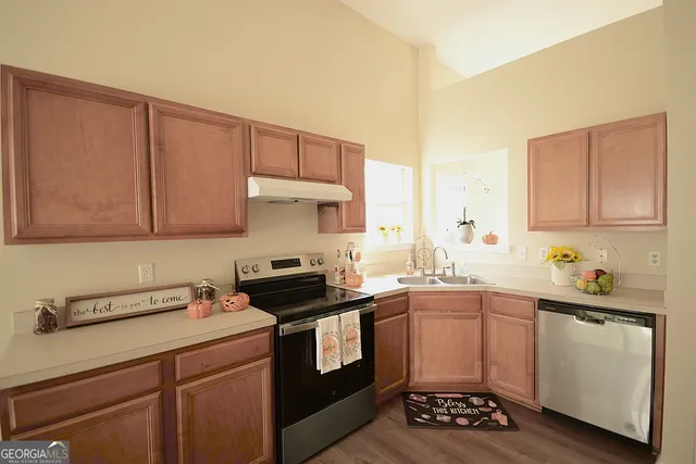 a kitchen with a sink a stove cabinets and wooden floor