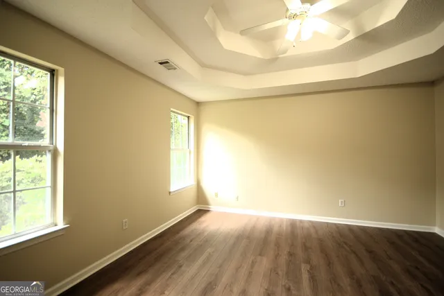 an empty room with wooden floor and windows