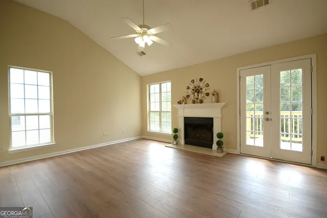 an empty room with wooden floor fireplace chandelier and windows