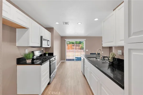 a kitchen with a sink dishwasher stove and white cabinets
