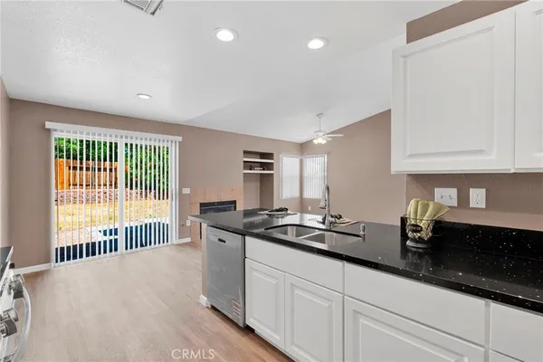a kitchen with granite countertop a sink and white cabinets