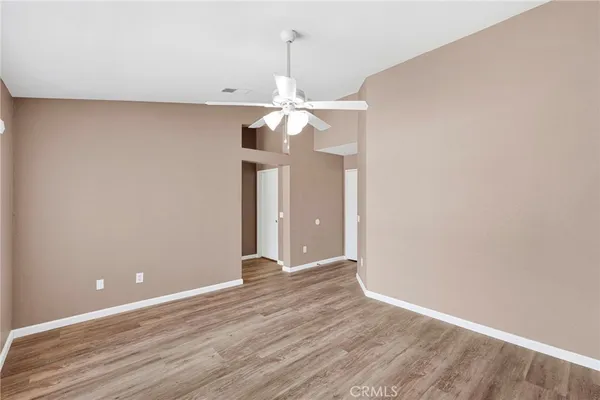 a view of a room with a chandelier fan and wooden floor