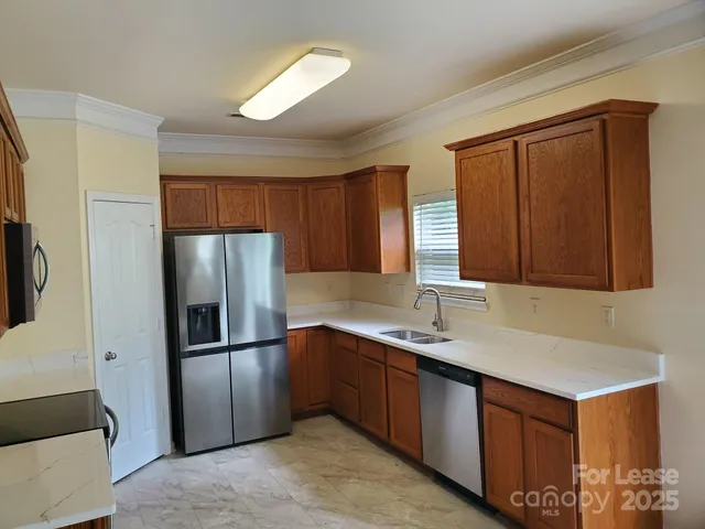 a kitchen with stainless steel appliances granite countertop a refrigerator a sink and a cabinets