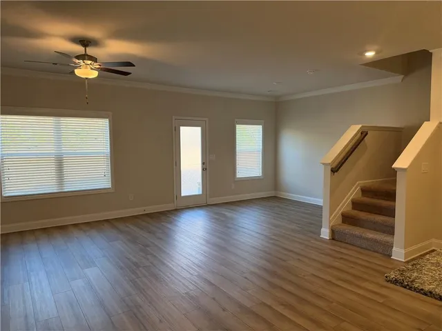a view of an empty room with wooden floor and fan