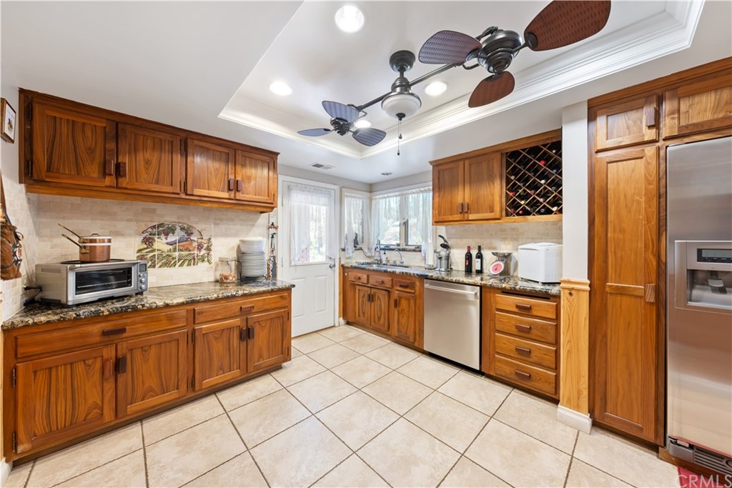 34970 Santa Rita Road Temecula, CA 92592 - Photo 23 of 38 a kitchen with stainless steel appliances granite countertop a refrigerator a sink dishwasher a stove top oven a dining table and chairs with wooden floor