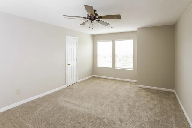 an empty room with a window and a fan