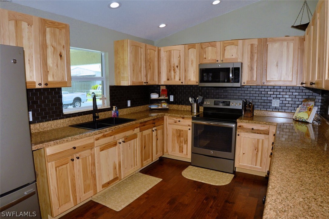 2041 Rialto Way Alva, FL 33920 - Photo 10 of 32 a kitchen with granite countertop a sink a stove top oven and cabinetry