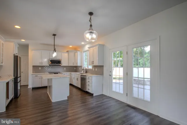 a kitchen with stainless steel appliances granite countertop a sink a stove a refrigerator cabinets and a kitchen island