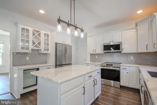 a kitchen with stainless steel appliances granite countertop a sink a stove cabinets and wooden floor