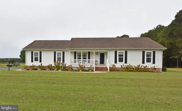 a front view of a house with a garden and trees