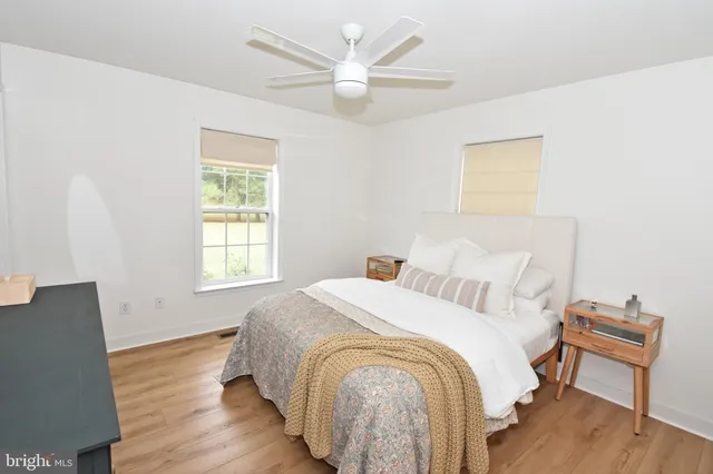 a spacious bedroom with a bed and a chair with wooden floor