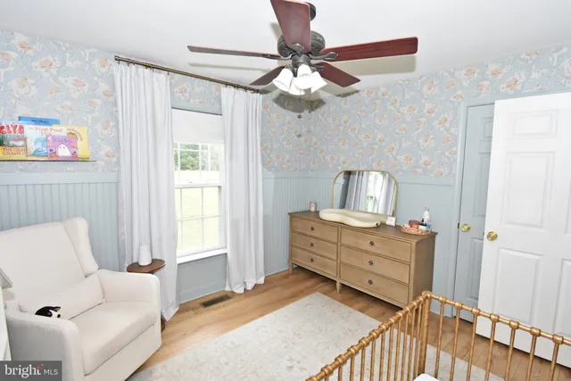 a workspace with wooden floor a ceiling fan and a window