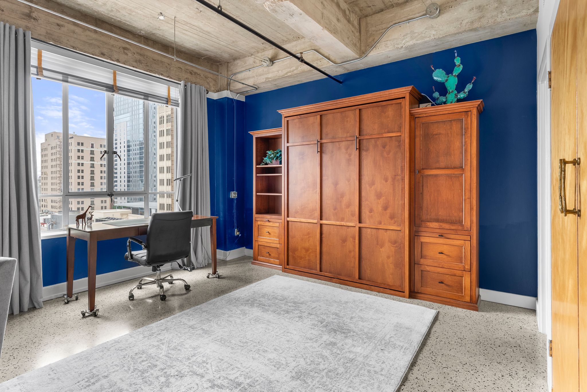710 Colorado Street, Unit 6E Austin, TX 78701 - Photo 8 of 24 City views and exposed concrete ceilings frame a versatile living space with a cleverly integrated Murphy bed.