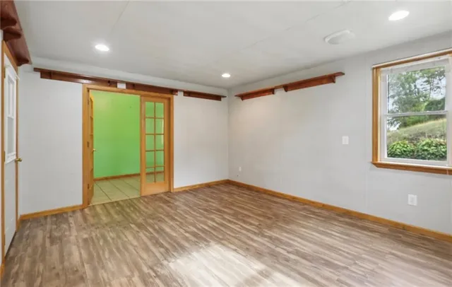a view of an empty room with wooden floor and a window