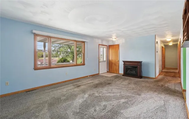 an empty room with windows fireplace and chandelier fan