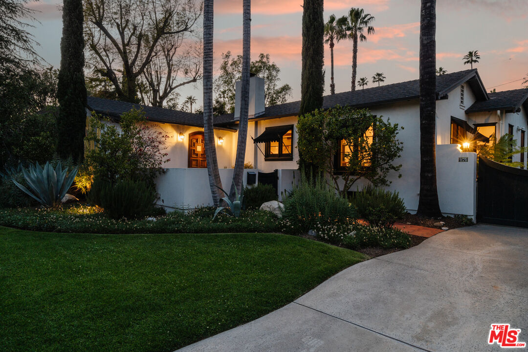 a front view of a house with a garden and trees