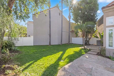 a view of a house with a big yard plants and large tree