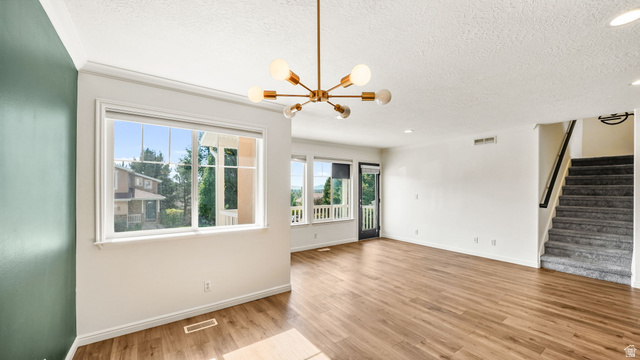 Open-concept living space with wood-finish flooring, a contemporary chandelier, and multiple windows