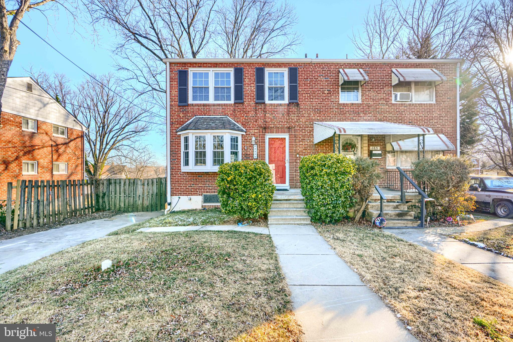 a view of a brick house with a yard and large trees