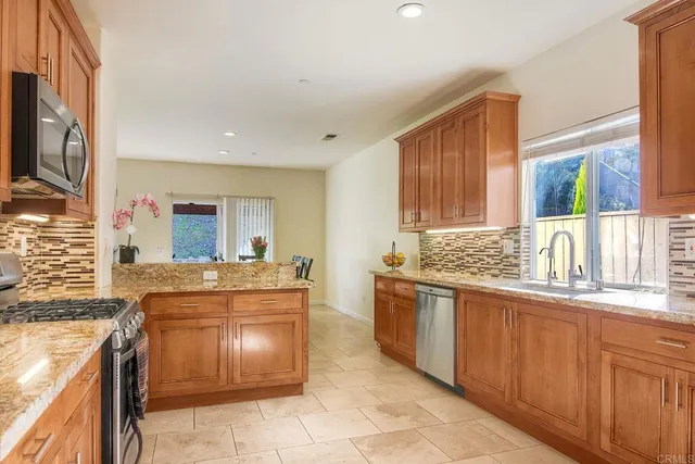 a kitchen with kitchen island granite countertop a stove sink and cabinets