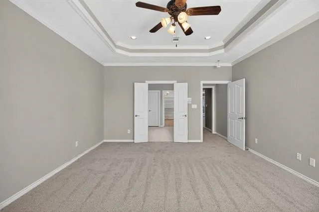 a view of an empty room and chandelier fan