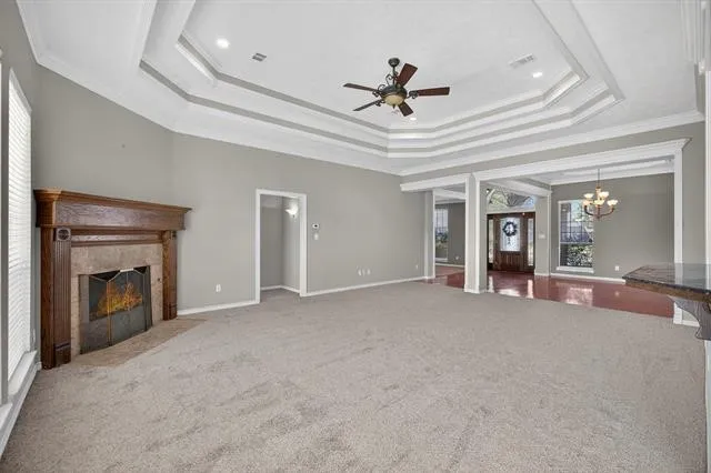 a view of an empty room with chandelier fan and fire place