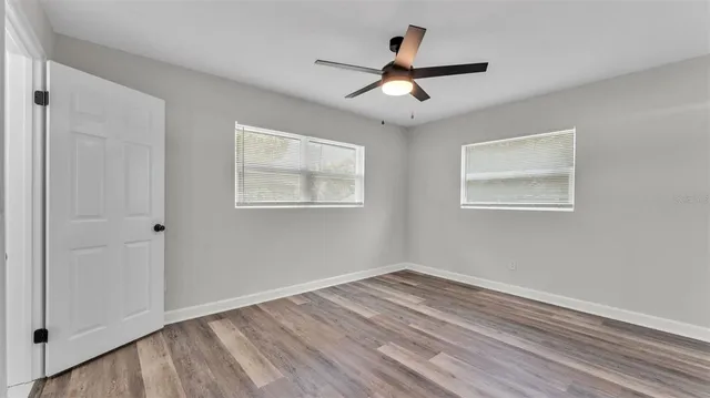 a view of empty room with wooden floor and fan