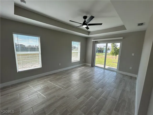 a view of an empty room with a window and wooden floor