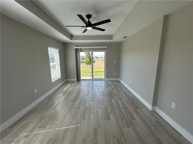 a view of empty room with wooden floor and ceiling fan