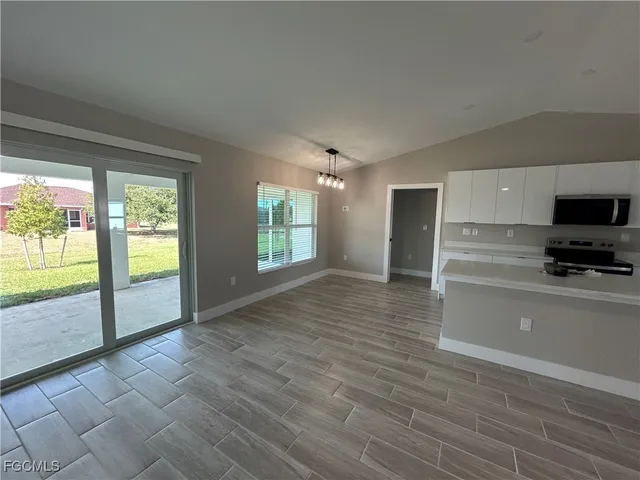 a view of an empty room with a window and a kitchen