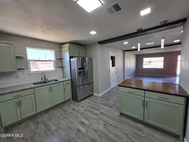 a kitchen with stainless steel appliances kitchen island granite countertop a refrigerator and a sink