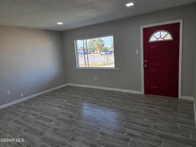 an empty room with wooden floor closet and windows