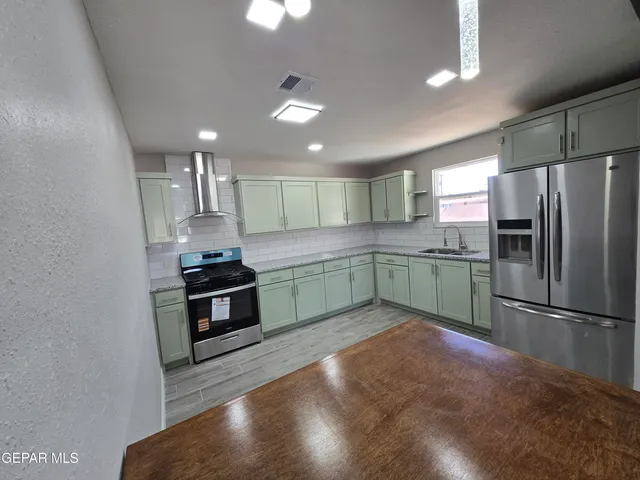 a kitchen with stainless steel appliances granite countertop a sink a stove a refrigerator and island