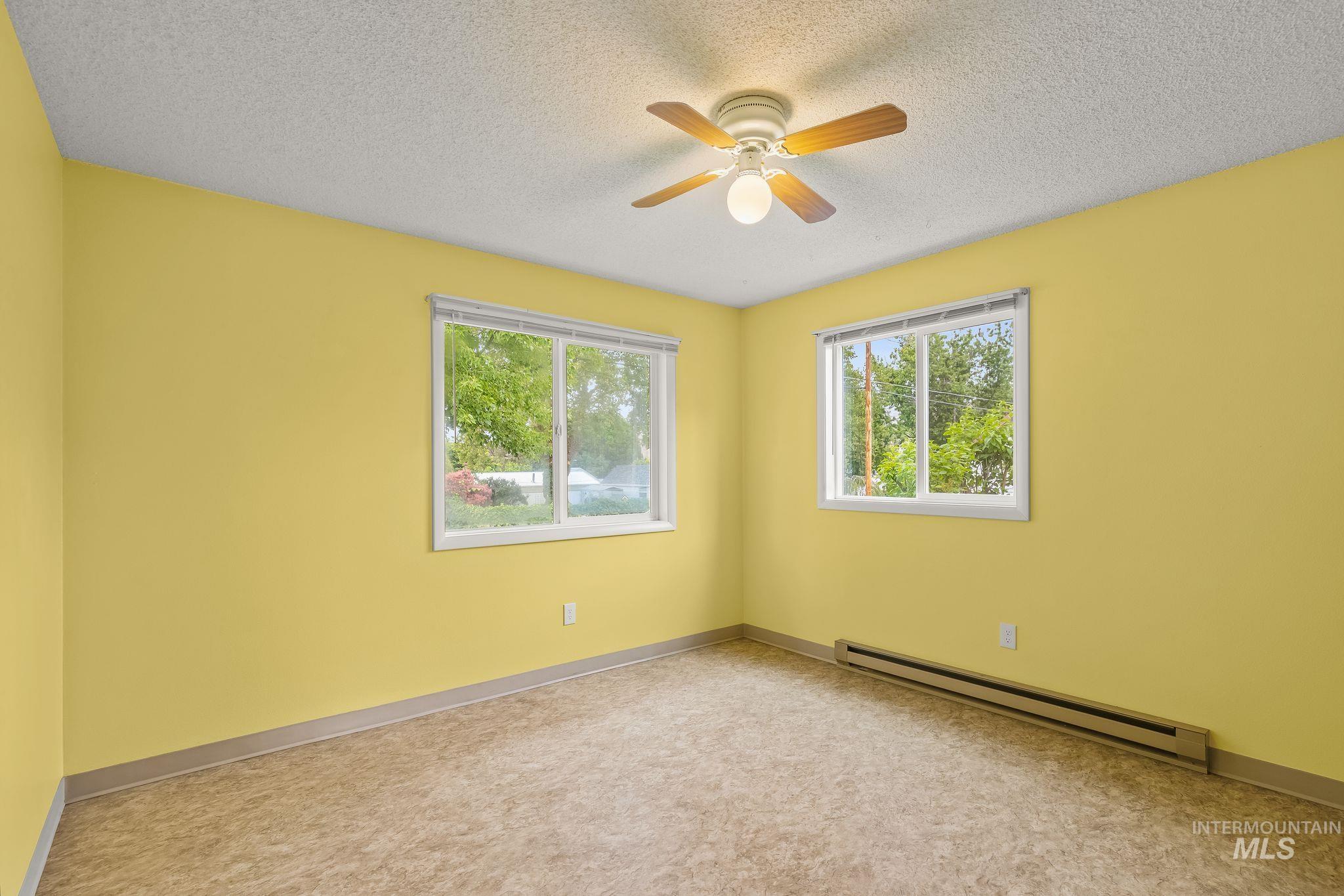 1721 3rd Street Lewiston, ID 83501 - Photo 39 of 45 Spacious room featuring two large windows, a ceiling fan with light fixture, and baseboard heating