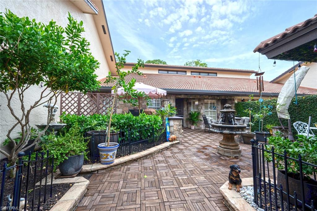 644 Augusta Boulevard Naples, FL 34113 - Photo 34 of 40 a view of a patio with table and chairs potted plants and large tree