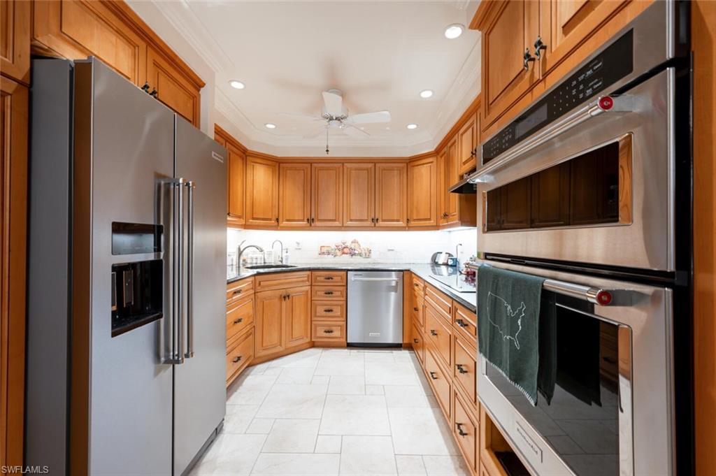644 Augusta Boulevard Naples, FL 34113 - Photo 7 of 40 a kitchen with stainless steel appliances granite countertop a refrigerator a stove and a sink with wooden floor