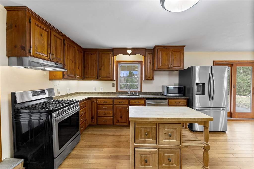 147 Worthington Road Huntington, MA 01050 - Photo 5 of 39 a kitchen with stainless steel appliances granite countertop a stove top oven a sink dishwasher and a refrigerator with wooden cabinets