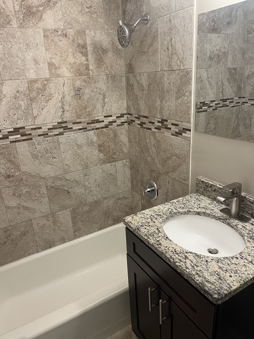 7501 SW Highway, Unit 5 Worth, IL 60482 - Photo 7 of 7 a bathroom with a granite countertop sink and a bathtub