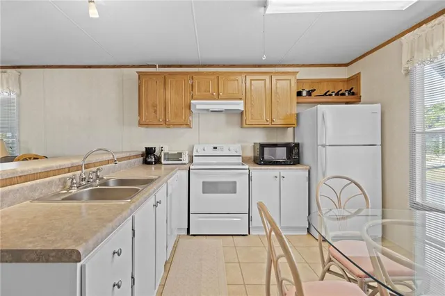a kitchen with stainless steel appliances granite countertop white cabinets a dining table and chairs