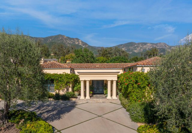 a front view of a house with a yard and mountain view in back